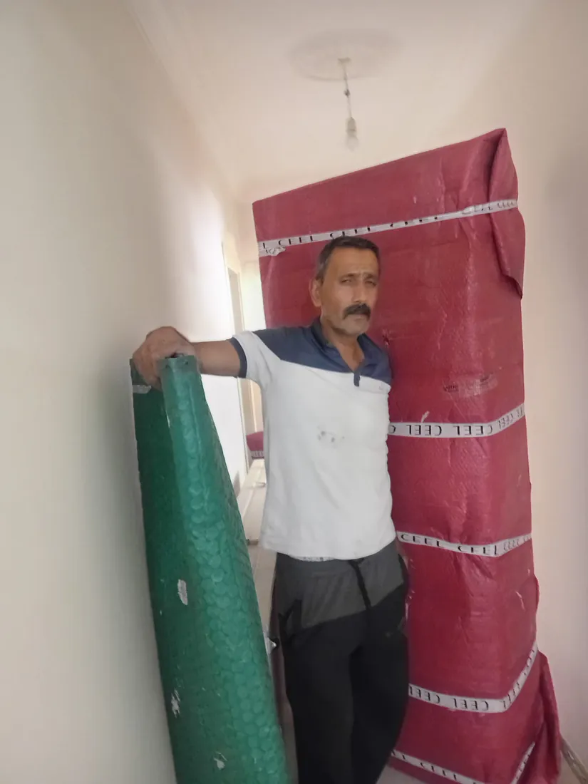 Özbek Nakliyat çalışanı, koruyucu malzemeyle paketlenmiş eşyaların yanında